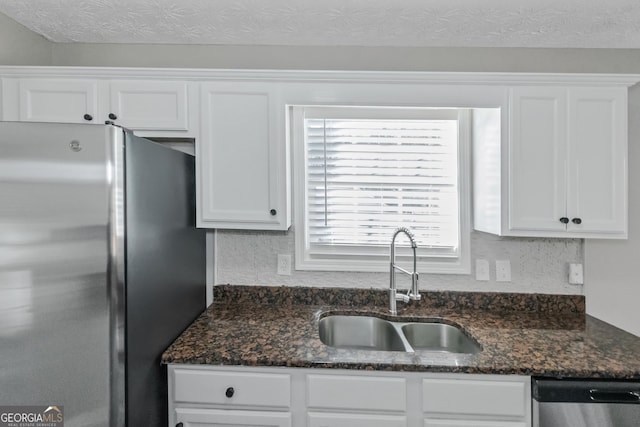 kitchen featuring stainless steel appliances, white cabinetry, dark stone countertops, and sink