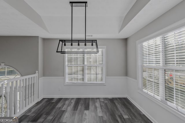 unfurnished dining area with plenty of natural light, dark hardwood / wood-style floors, and an inviting chandelier