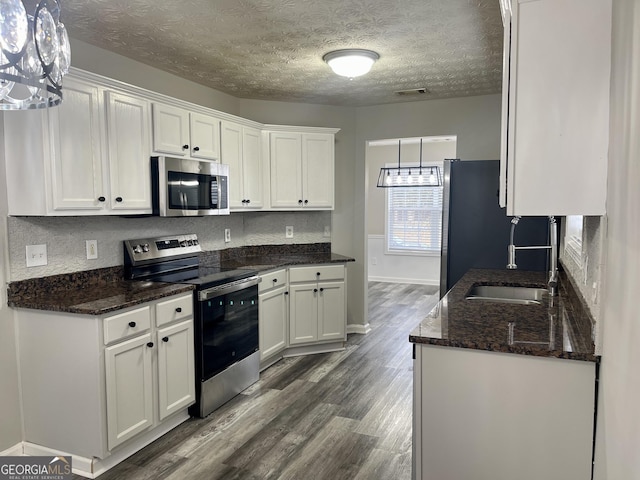 kitchen with pendant lighting, white cabinetry, and appliances with stainless steel finishes