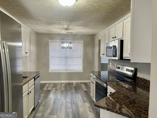 kitchen featuring white cabinetry, dark wood-type flooring, stainless steel appliances, a chandelier, and decorative light fixtures