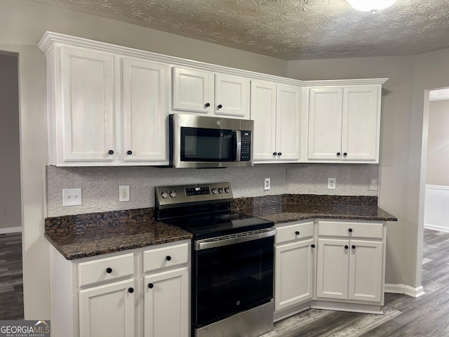 kitchen featuring dark wood-type flooring, white cabinets, stainless steel appliances, and a textured ceiling