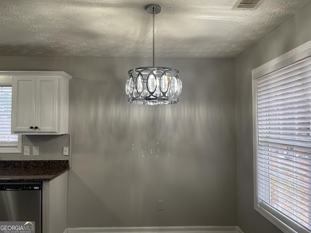 unfurnished dining area with a chandelier and a textured ceiling