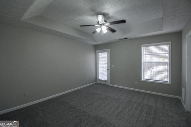 carpeted spare room featuring a raised ceiling, ceiling fan, and a textured ceiling