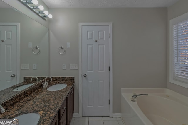 bathroom featuring tile patterned floors, a bathtub, vanity, and a textured ceiling