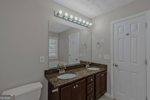 bathroom featuring tile patterned floors, a bathtub, vanity, a textured ceiling, and toilet