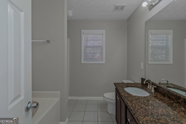 bathroom with a washtub, tile patterned floors, a textured ceiling, toilet, and vanity