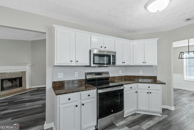 kitchen with white cabinetry, dark hardwood / wood-style floors, a textured ceiling, and appliances with stainless steel finishes