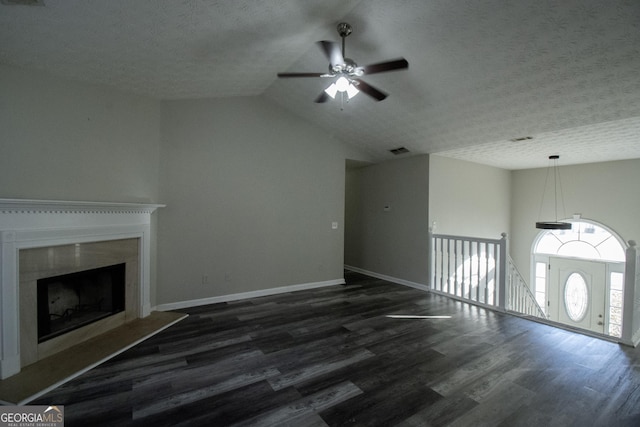 unfurnished living room with ceiling fan, dark hardwood / wood-style flooring, lofted ceiling, a textured ceiling, and a fireplace