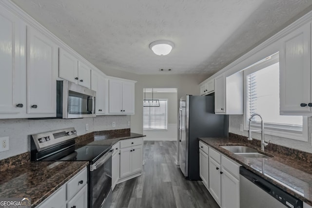 kitchen with sink, a textured ceiling, appliances with stainless steel finishes, dark hardwood / wood-style flooring, and white cabinetry