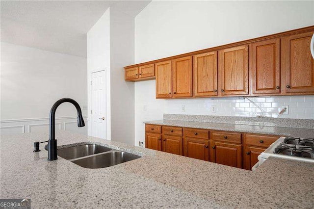 kitchen with range, light stone countertops, sink, and backsplash