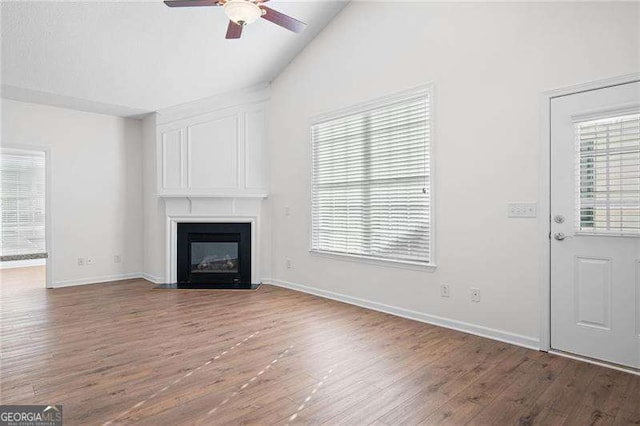 unfurnished living room with wood-type flooring, vaulted ceiling, ceiling fan, and a fireplace