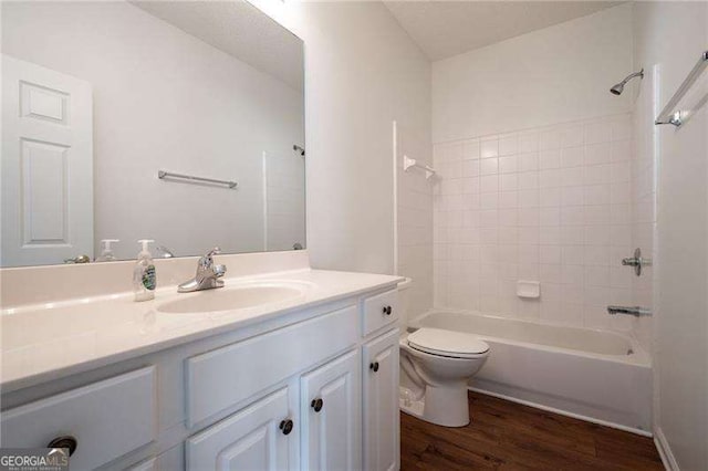 full bathroom with wood-type flooring, toilet, tiled shower / bath combo, and vanity