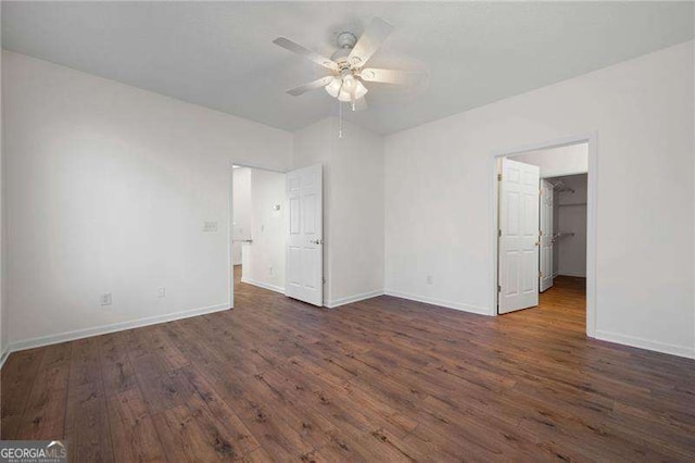 unfurnished bedroom with ceiling fan, a walk in closet, and dark hardwood / wood-style floors