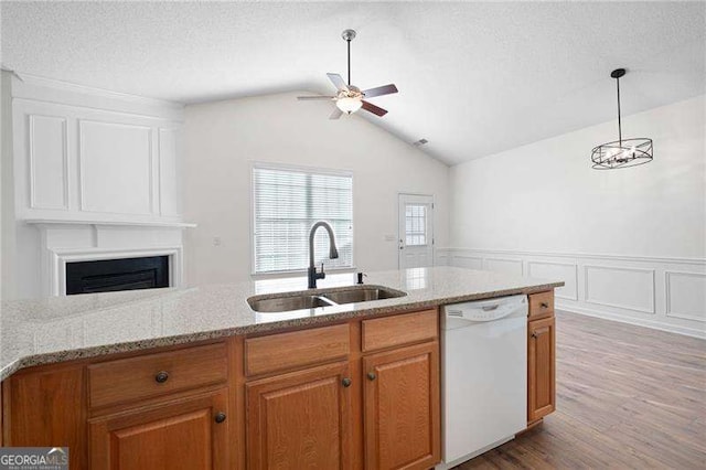 kitchen with sink, dishwasher, light stone countertops, decorative light fixtures, and vaulted ceiling