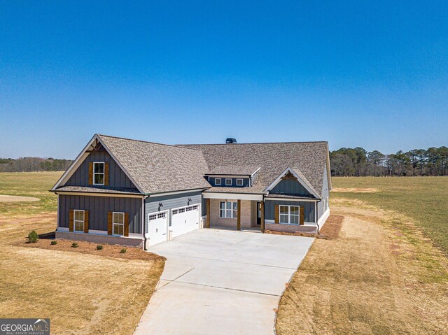 view of front of property featuring driveway, an attached garage, a shingled roof, a front lawn, and board and batten siding