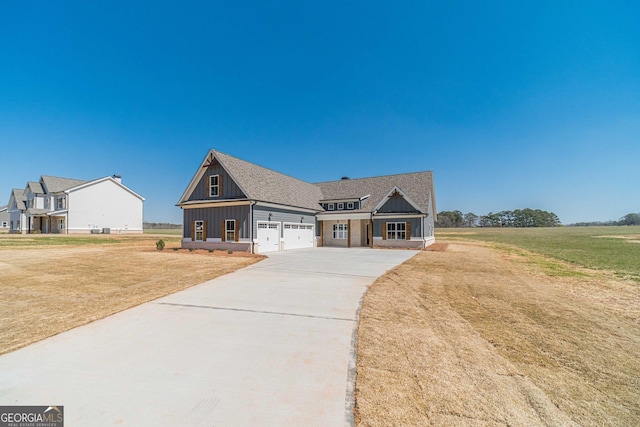 view of front of house featuring a front lawn, driveway, board and batten siding, roof with shingles, and an attached garage