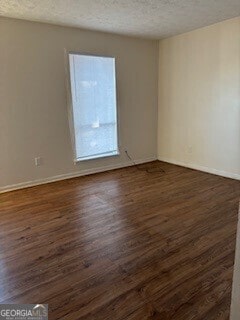 unfurnished room with a textured ceiling and dark hardwood / wood-style floors