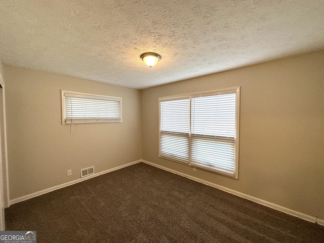 carpeted empty room featuring a textured ceiling