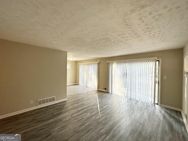 spare room featuring a textured ceiling and dark hardwood / wood-style floors