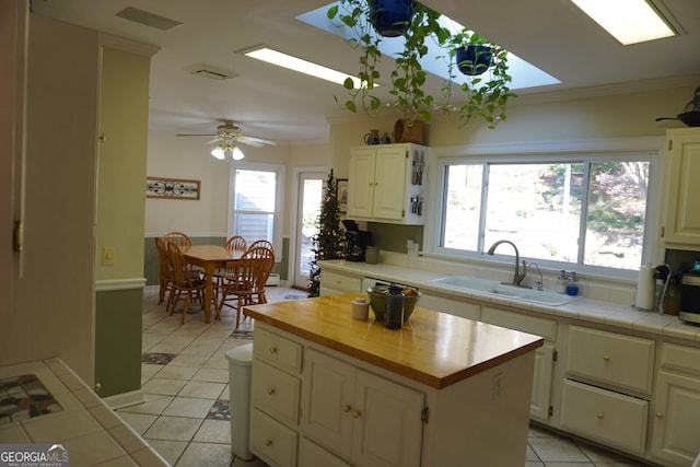 kitchen with a kitchen island, sink, tile counters, crown molding, and a healthy amount of sunlight