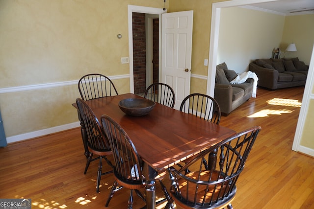 dining space with crown molding and light wood-type flooring