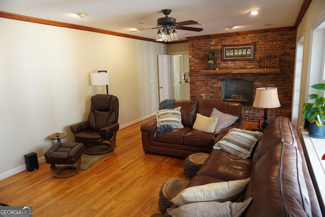 living room with crown molding, ceiling fan, a brick fireplace, and light hardwood / wood-style flooring