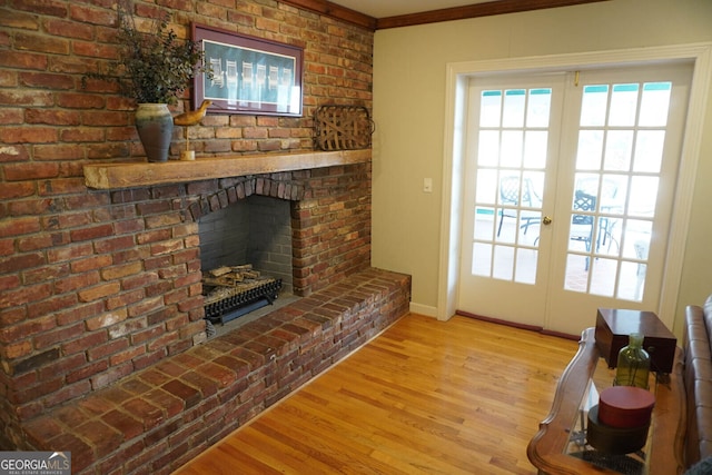 living room with french doors, a brick fireplace, and light wood-type flooring