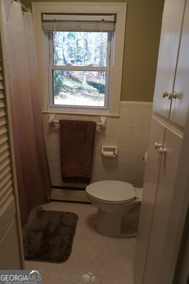 bathroom featuring tile walls, tile patterned flooring, a baseboard radiator, and toilet