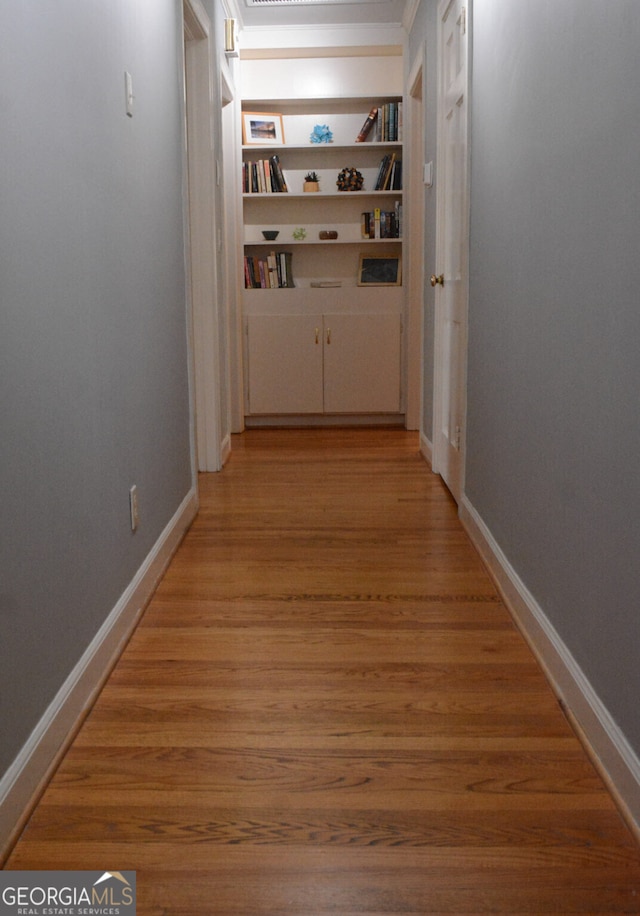 hall with light hardwood / wood-style floors and built in shelves