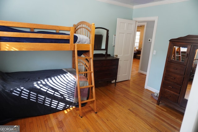 bedroom with ornamental molding and light hardwood / wood-style floors