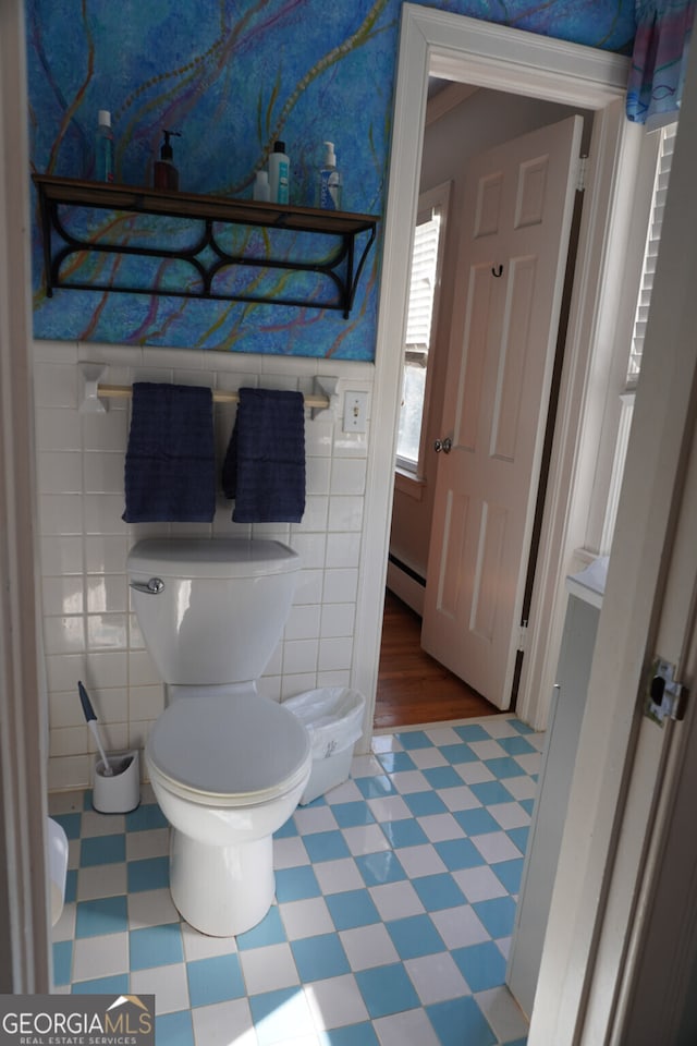 bathroom featuring a baseboard radiator, tile walls, and toilet