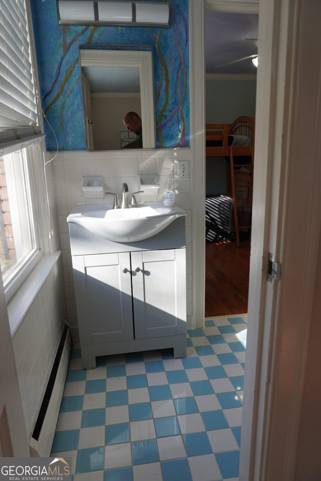 bathroom featuring vanity, crown molding, a baseboard radiator, and tile walls