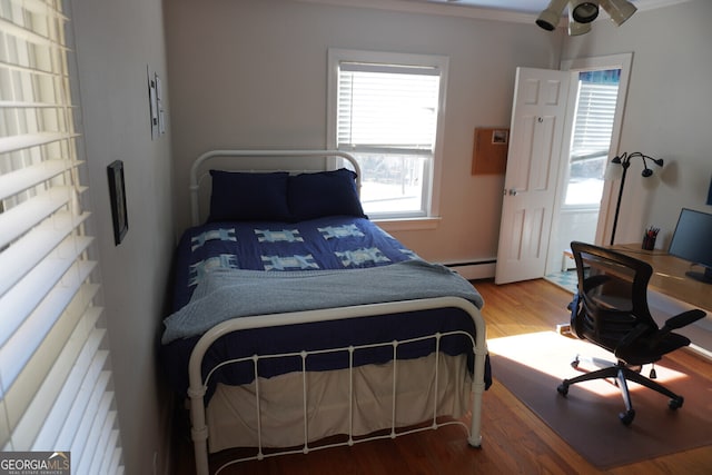 bedroom with a baseboard heating unit and hardwood / wood-style flooring