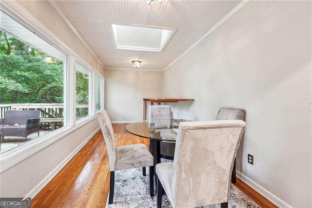 dining area with hardwood / wood-style floors, a skylight, and crown molding