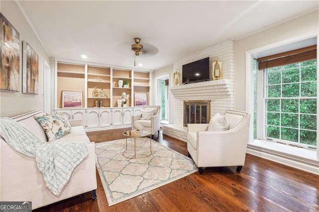 living room with a wealth of natural light, ceiling fan, dark hardwood / wood-style floors, and a brick fireplace