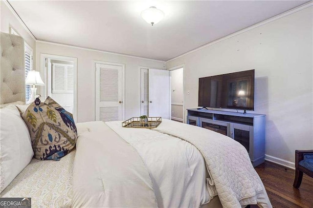 bedroom with multiple closets, hardwood / wood-style floors, and ornamental molding