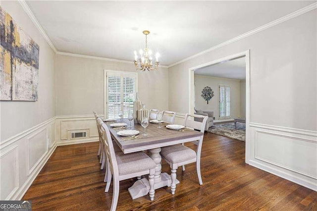 dining space with dark hardwood / wood-style flooring, ornamental molding, and a chandelier