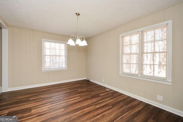 spare room with dark hardwood / wood-style floors and a chandelier