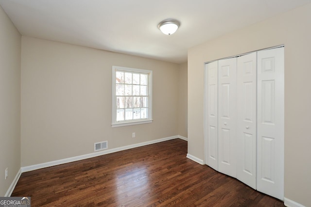 unfurnished bedroom with dark hardwood / wood-style floors and a closet