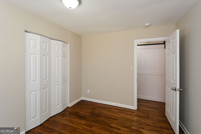 unfurnished bedroom with a closet and dark wood-type flooring