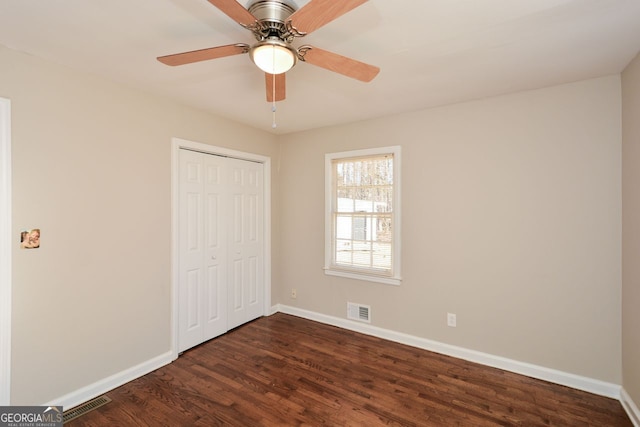 unfurnished bedroom with ceiling fan, a closet, and dark wood-type flooring