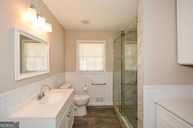 bathroom with toilet, vanity, and a shower with door