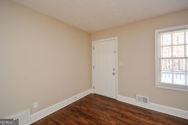 spare room with dark hardwood / wood-style floors and a textured ceiling