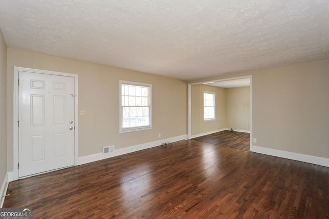 unfurnished room with dark hardwood / wood-style flooring and a textured ceiling