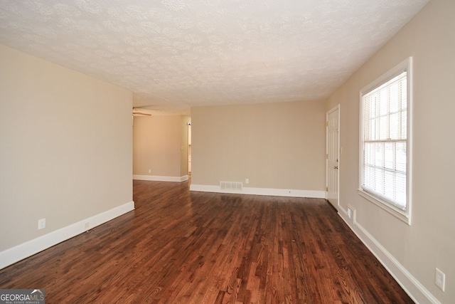 unfurnished room featuring a textured ceiling and dark hardwood / wood-style flooring