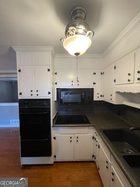 kitchen with black appliances, white cabinetry, and sink