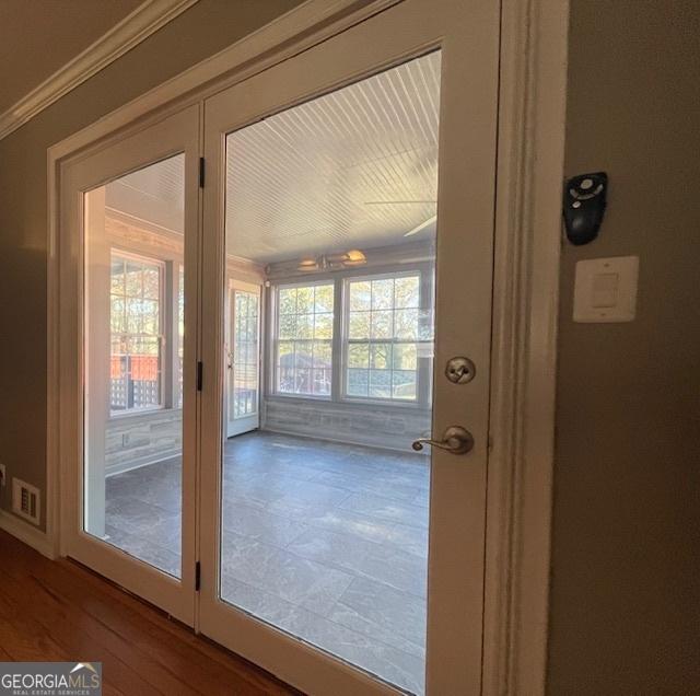 entryway featuring wood-type flooring and crown molding