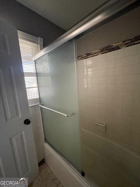 bathroom featuring bath / shower combo with glass door