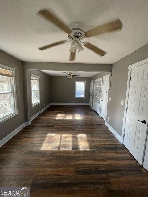 unfurnished room with ceiling fan and dark wood-type flooring