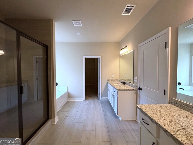 bathroom with vanity and shower with separate bathtub